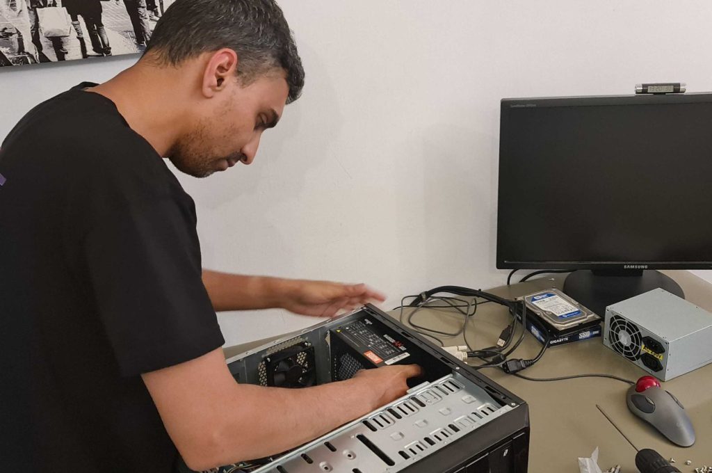 משה הטכנאי מתקן מחשב נייח מפורק על השולחן